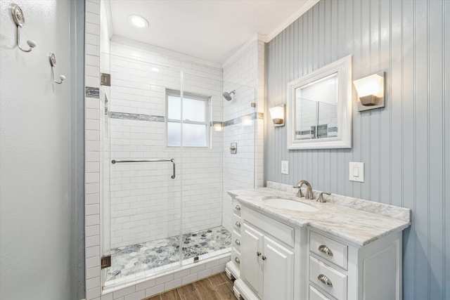 full bath with vanity, a shower stall, and wood finished floors