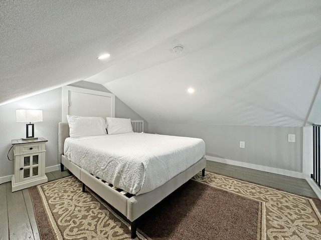 bedroom with a textured ceiling, baseboards, lofted ceiling, and wood finished floors