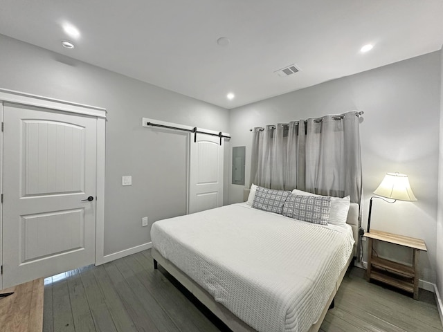 bedroom featuring visible vents, hardwood / wood-style floors, recessed lighting, a barn door, and baseboards