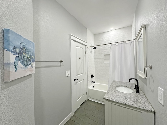 full bath featuring shower / tub combo, wood finished floors, vanity, and a textured wall