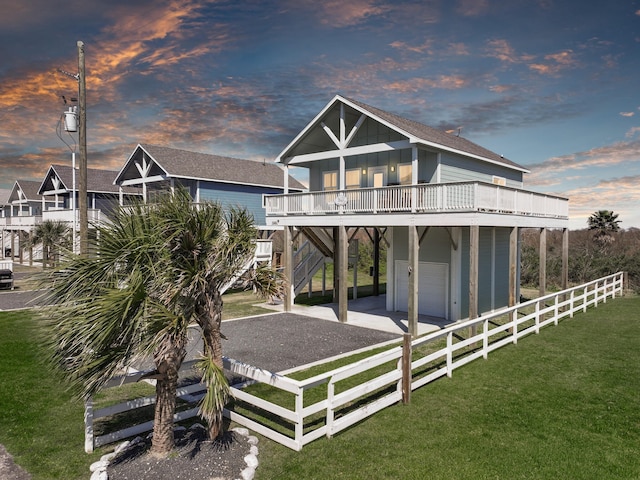 back of property featuring board and batten siding, fence, stairs, a lawn, and driveway