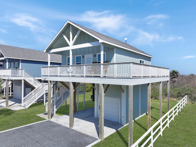 rear view of property with a lawn, board and batten siding, driveway, and roof with shingles