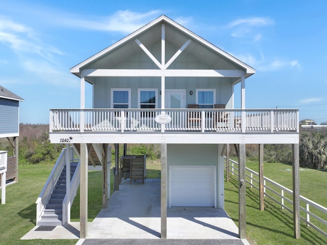 raised beach house with board and batten siding, a front lawn, stairs, a garage, and a carport