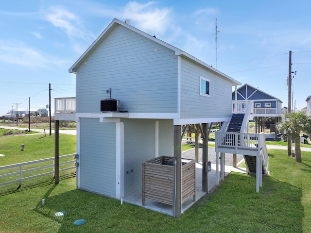 view of home's exterior featuring stairway, cooling unit, a lawn, and fence