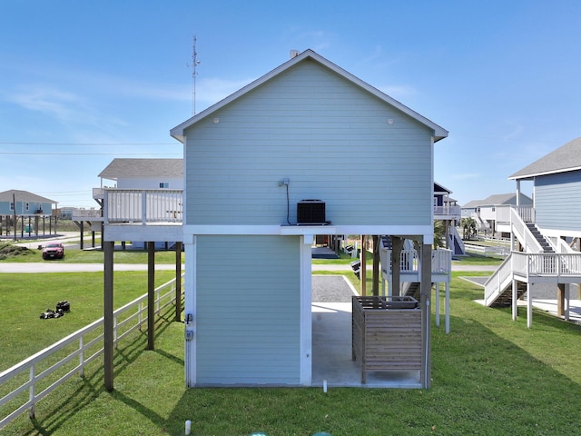 view of property exterior with stairway, fence, driveway, a carport, and a lawn