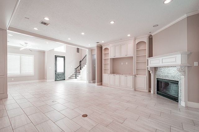 unfurnished living room featuring visible vents, ornamental molding, stairs, and a tile fireplace