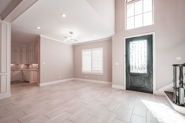 foyer entrance featuring a notable chandelier, light wood-style flooring, crown molding, and baseboards