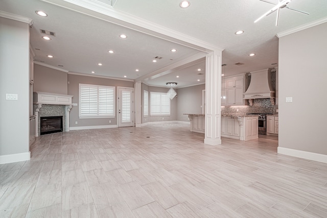 unfurnished living room featuring visible vents, baseboards, a glass covered fireplace, and ornamental molding