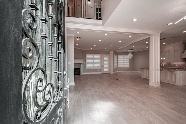 foyer entrance featuring recessed lighting, a fireplace, light wood-style floors, and ornamental molding