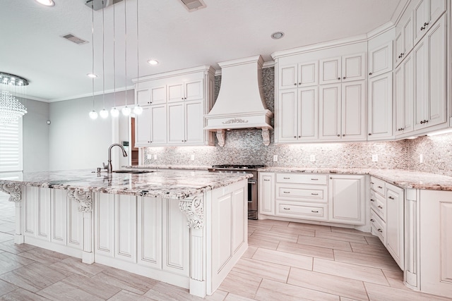 kitchen featuring visible vents, a large island with sink, stainless steel stove, custom exhaust hood, and a sink