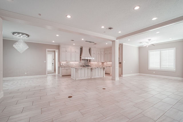 unfurnished living room with visible vents, baseboards, a chandelier, ornamental molding, and a textured ceiling