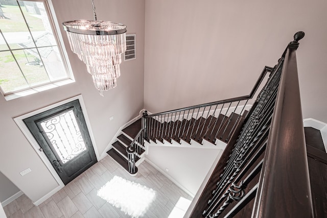 entrance foyer featuring visible vents, baseboards, an inviting chandelier, and stairs