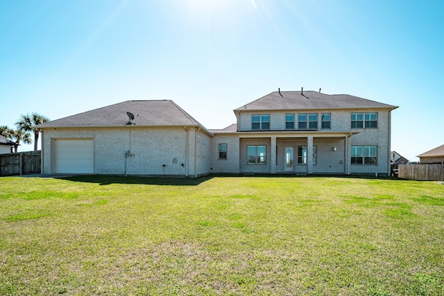 back of property with a garage, a lawn, and fence