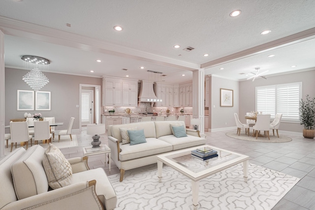 living area featuring light tile patterned floors, visible vents, a textured ceiling, crown molding, and a notable chandelier