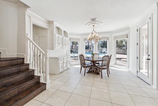 dining space featuring ornamental molding, a textured ceiling, light tile patterned floors, a chandelier, and stairs