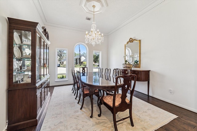 dining area with visible vents, baseboards, wood finished floors, and crown molding