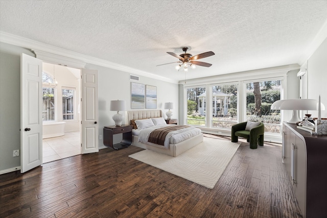 bedroom featuring dark wood finished floors, a textured ceiling, visible vents, and ornamental molding