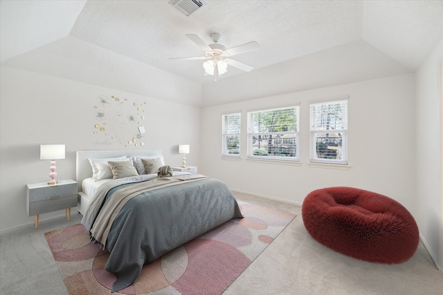 bedroom with a raised ceiling, baseboards, visible vents, and light carpet