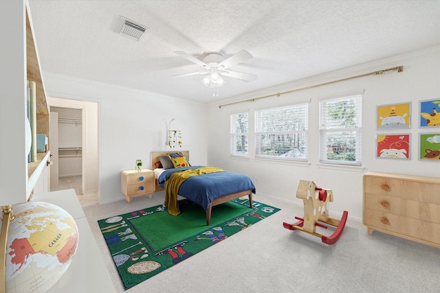 bedroom with visible vents, crown molding, ceiling fan, light colored carpet, and a textured ceiling