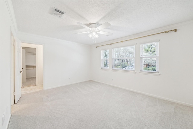 spare room featuring baseboards, visible vents, a textured ceiling, crown molding, and light carpet