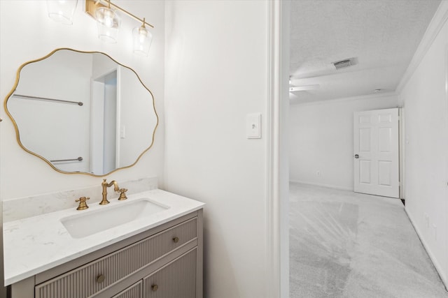 bathroom featuring visible vents, a textured ceiling, vanity, and crown molding