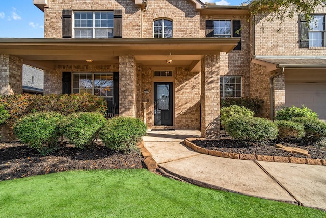 view of exterior entry featuring a garage and brick siding