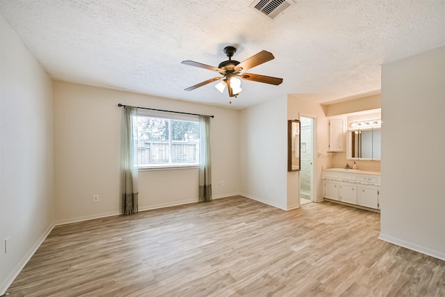 unfurnished bedroom featuring a sink, visible vents, baseboards, and light wood finished floors