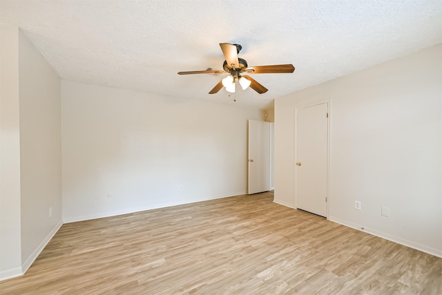 empty room featuring ceiling fan, baseboards, a textured ceiling, and light wood-style flooring