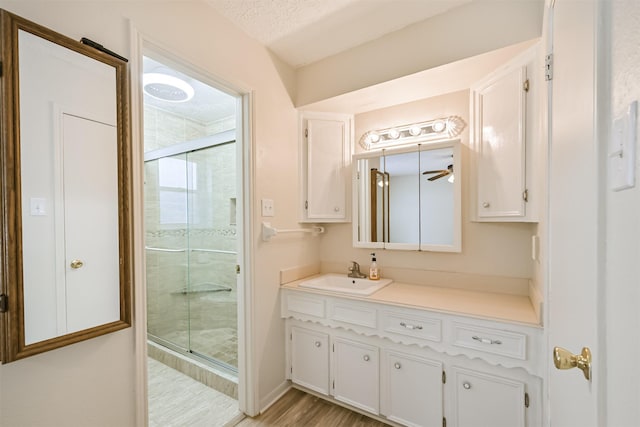 bathroom with wood finished floors, a textured ceiling, a stall shower, and vanity