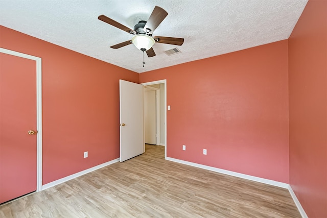 unfurnished bedroom featuring a textured ceiling, baseboards, light wood-style floors, and a ceiling fan