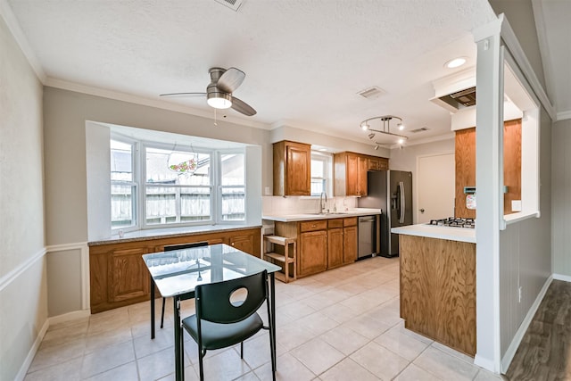 kitchen featuring visible vents, brown cabinets, a sink, stainless steel appliances, and crown molding