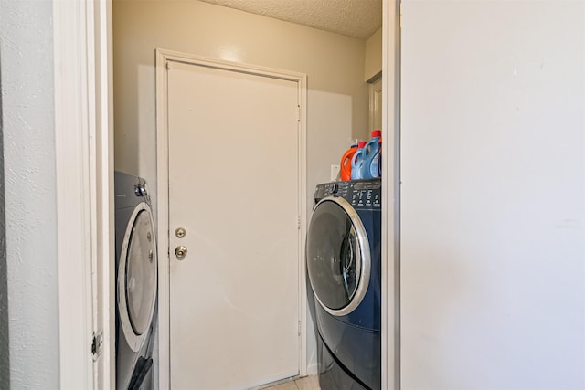 clothes washing area featuring laundry area, a textured ceiling, and washer / clothes dryer