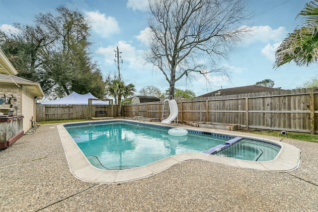 view of pool with a patio area, a pool with connected hot tub, a water slide, and a fenced backyard