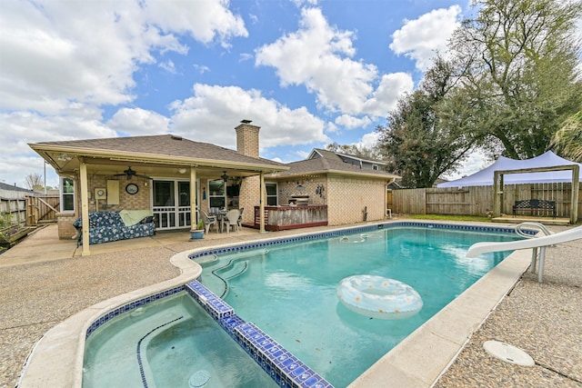 view of swimming pool featuring a pool with connected hot tub, a water slide, ceiling fan, a fenced backyard, and a patio