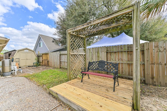 deck featuring a storage unit, a fenced backyard, and an outdoor structure