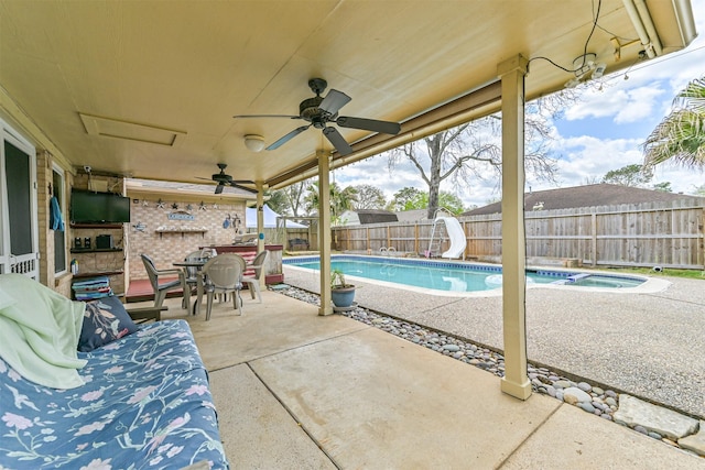 view of swimming pool featuring a fenced in pool, a water slide, a fenced backyard, ceiling fan, and a patio area