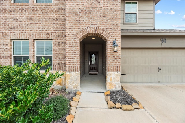 property entrance with brick siding, stone siding, and driveway