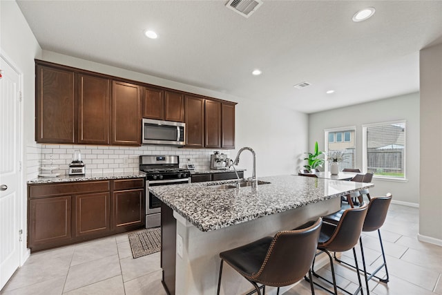 kitchen with light stone counters, visible vents, a sink, stainless steel appliances, and tasteful backsplash