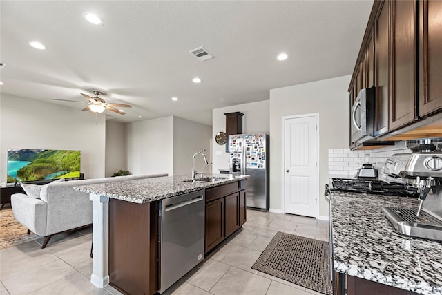 kitchen featuring a sink, light stone countertops, appliances with stainless steel finishes, and dark brown cabinets