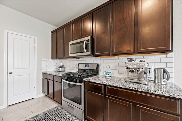 kitchen with tasteful backsplash, light stone countertops, dark brown cabinetry, light tile patterned floors, and stainless steel appliances