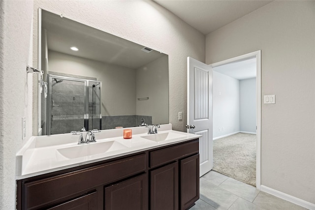 bathroom featuring double vanity, tile patterned flooring, a shower stall, and a sink