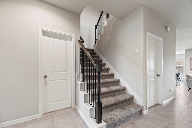 stairs featuring tile patterned floors and baseboards