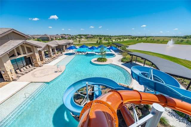 pool with a patio area, a water slide, and a water play area