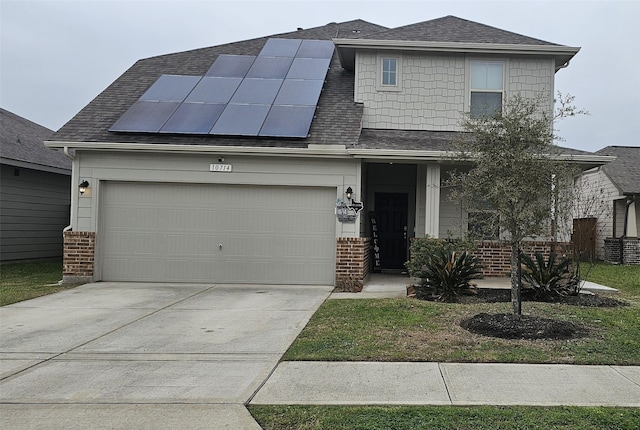 view of front of home featuring roof mounted solar panels, brick siding, roof with shingles, and driveway