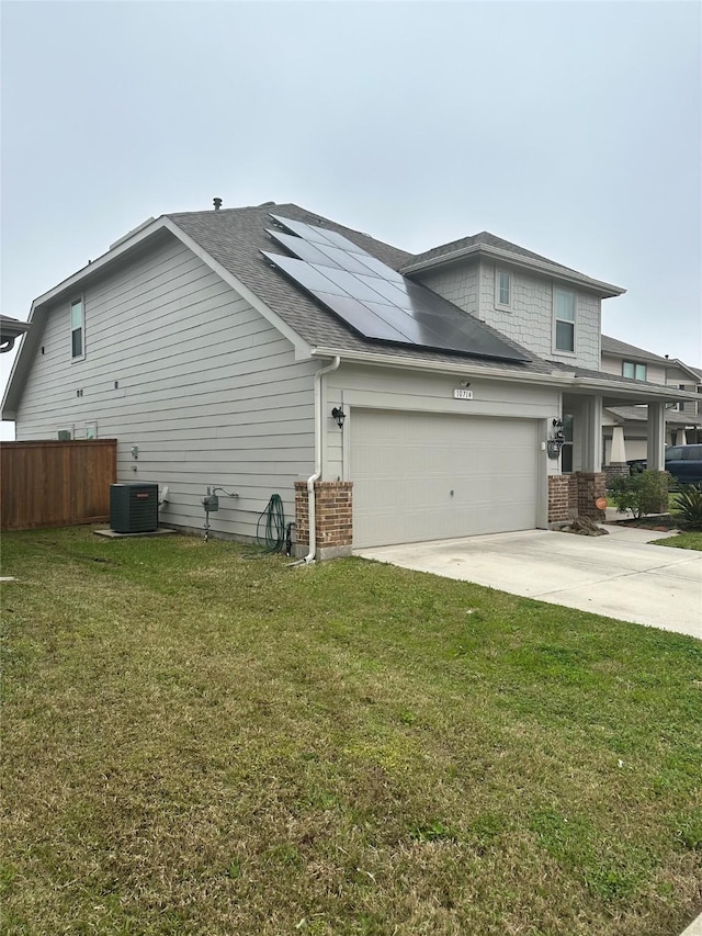 view of side of property featuring a yard, cooling unit, an attached garage, brick siding, and solar panels