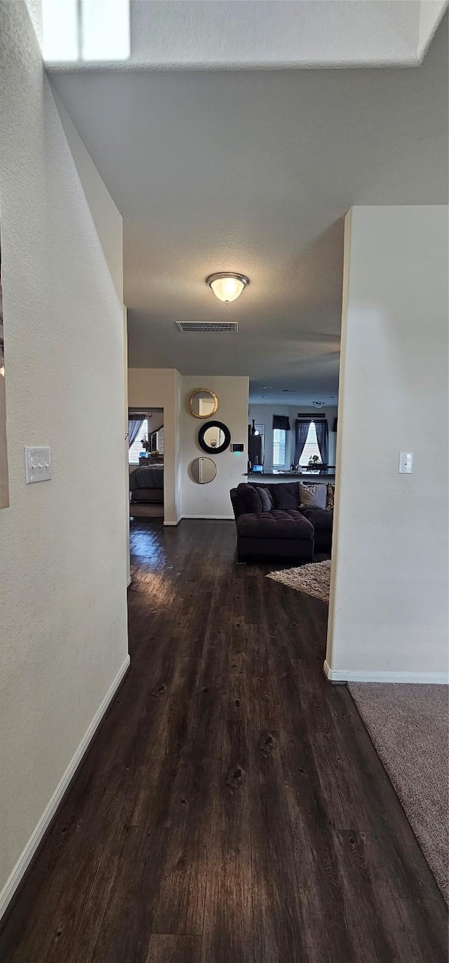 corridor featuring visible vents, wood finished floors, and baseboards