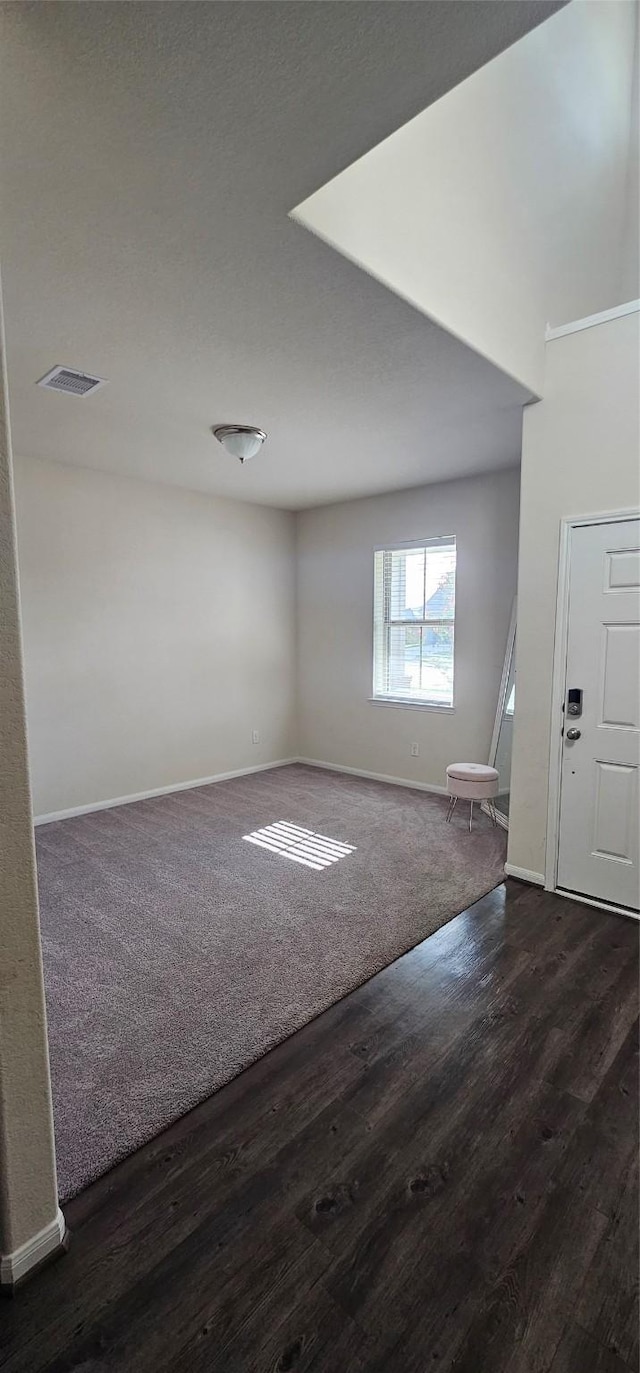 spare room with wood finished floors, visible vents, and baseboards