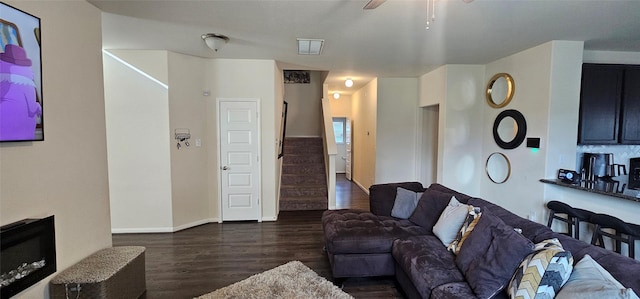 living room featuring dark wood-type flooring, stairway, baseboards, and ceiling fan