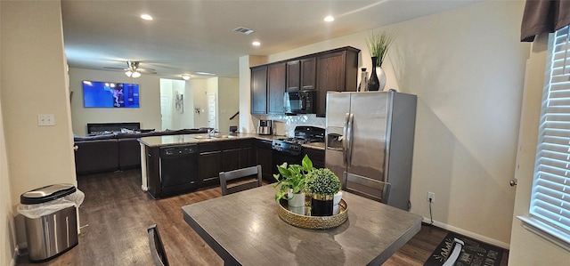 kitchen featuring visible vents, a peninsula, black appliances, and dark wood-style floors