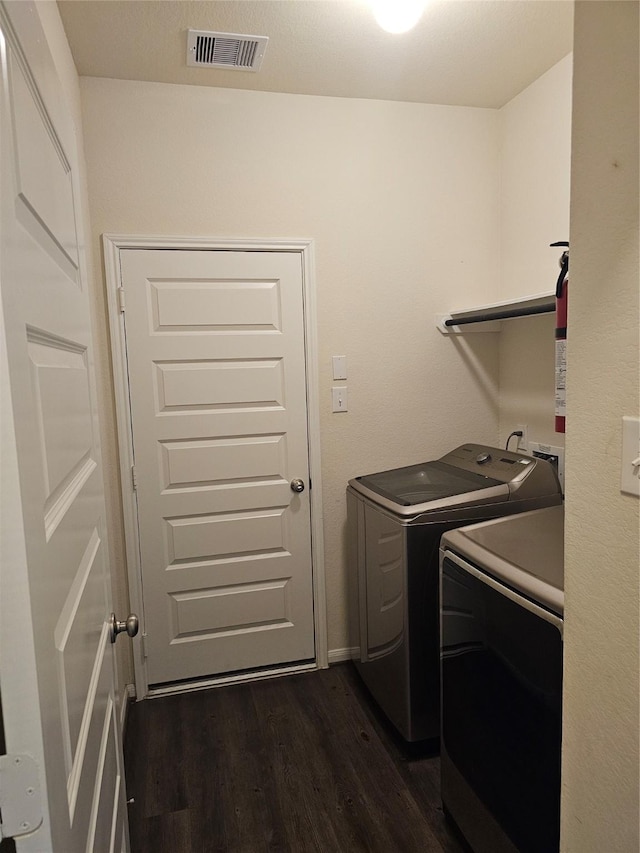 laundry area featuring visible vents, dark wood-type flooring, laundry area, and washer and clothes dryer